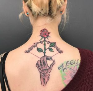Traditional bow and Rose arrow being shot by skeleton hand on back of woman's neck